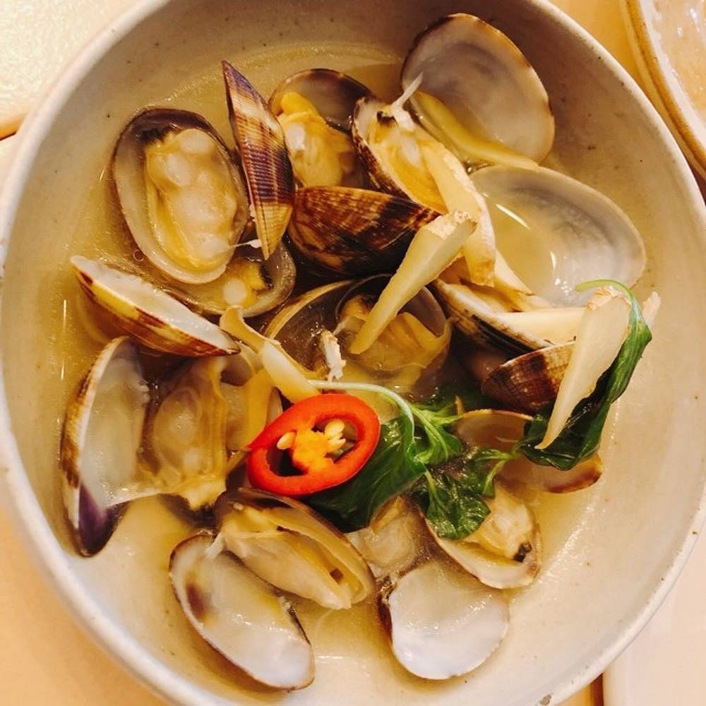 Before: dim phone photo of a bowl of clams in broth on a kitchen counter